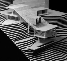 a model of a house sitting on top of a black and white striped surface