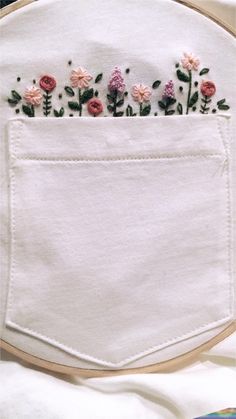 embroidered flowers are in the pocket of a white piece of cloth