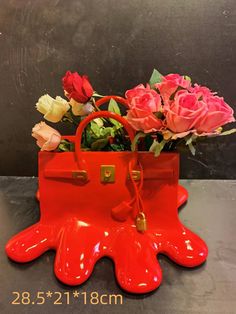 a red purse with flowers in it sitting on a table