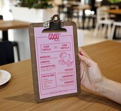 a person holding a clipboard with a menu attached to it on a table in a restaurant