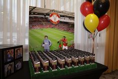 a table topped with drinks and balloons next to a photo on a large screen tv