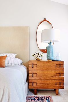 a bedroom with a bed, dresser and mirror on the wall above it's headboard