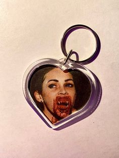 a heart shaped keychain with an image of a woman's face on it