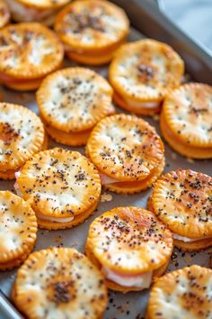 small crackers with cheese and pepper sprinkled on them in a baking pan