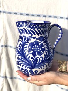 a hand holding a blue and white pitcher