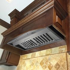 a kitchen hood is shown in the middle of an oven with dark wood cabinets and marble counter tops