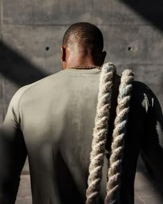 a man with dreadlocks standing in front of a wall and looking at something