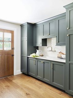 an empty kitchen with green cabinets and white counter tops, wood flooring and wooden doors