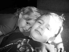 two young children laying on the couch with their arms around each other's shoulders