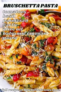 pasta with tomatoes, spinach and parmesan cheese in a white bowl on a table