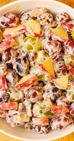 a white bowl filled with fruit salad on top of a wooden table