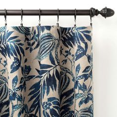 a blue and white floral curtain hanging on a rod with black metal rods in front of it