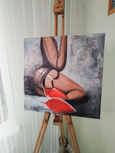 an easel with a painting on it and a woman's legs in high heels