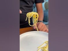 a person holding a fork with some noodles on it