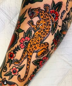 a tattoo on the leg of a woman with flowers and a leopard in its body