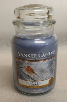 a yankee candle with a bird on it sitting in front of a white tablecloth