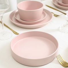 the table is set with pink plates and silverware