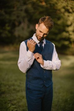 a man adjusting his tie while standing in the grass