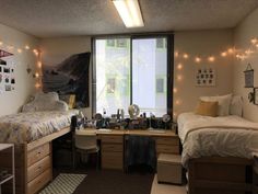 a dorm room with two beds, desk and lights on the windows sill above them