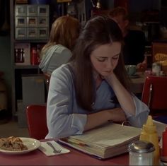 a woman sitting at a table reading a book