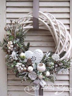 a christmas wreath hanging on the side of a door with pine cones and other decorations