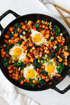 two eggs on top of some vegetables in a skillet