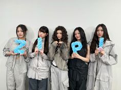 four women holding up question signs in front of a white wall