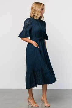 Simple and classic for every occasion Woven eyelet material Deep Navy Blue color Fit runs big, we recommend sizing down Banded collar with ruffle Functioning buttons down front of dress Mid-length sleeve with ruffle Natural waist with self-tie sash Midi length skirt with single tier Hidden side pockets Dress lined to top of tier, unlined sleeve Self: 100% Cotton, Lining: 97% Polyester, 3% Spandex Trina is 5'6, cup size 32D, size 2 and is wearing size XS Eyelet Midi Dress, Midi Dress Navy, Deep Navy Blue, Eyelet Fabric, Girls Tie, Romper Outfit, Navy Midi Dress, Midi Length Skirts, Wedding Dress Shopping