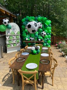 a table set up for a soccer themed birthday party with balloons and plates on it