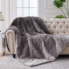 a living room with a couch and chair covered in a fluffy gray fur throw blanket