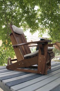 a wooden chair sitting on top of a wooden deck under a green leafy tree