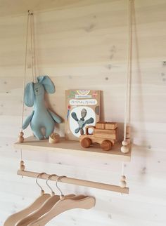 a toy elephant sitting on top of a wooden shelf next to a book and clothes hanger