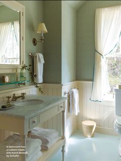 a bathroom with a toilet, sink and mirror in it's corner next to a window