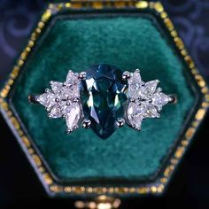 a fancy ring with blue and white stones in a green velvet box on top of a table