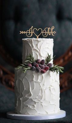 a white wedding cake decorated with berries and greenery