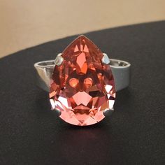 an orange colored diamond ring sitting on top of a black table next to a wall