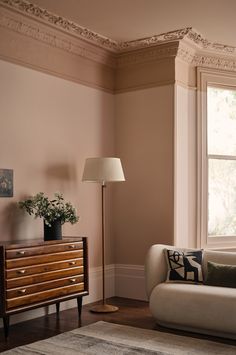 a living room with a couch, lamp and dresser in it's centerpiece