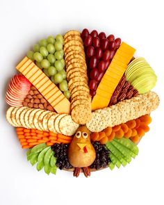 a turkey shaped platter with grapes, apples, crackers and cheeses on it