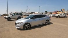 a silver car parked in a parking lot next to other cars and construction equipment behind it