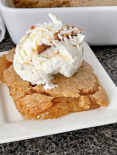 a piece of cake with ice cream on top is sitting on a square white plate