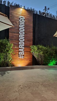 the entrance to an outdoor bar with lights on it's side and trees in front