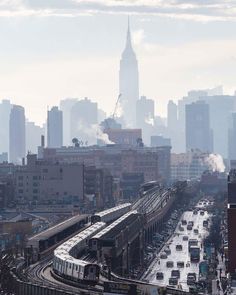 a train on the tracks in front of a cityscape with tall buildings and skyscrapers