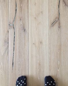 someone's feet in black and white polka dot slippers standing on wood floor