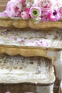 pink flowers are sitting on top of an antique table