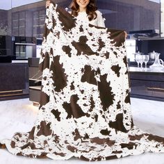 a woman holding up a cow print blanket