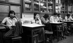 a group of people sitting at desks in a room with books on the shelves