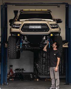 a man standing in front of a lifted up truck with the words tacoma on it