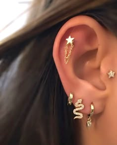 a woman wearing three different ear piercings on her left ear and one with two stars