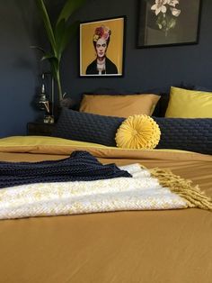 a bed with yellow sheets and blankets on it in a room that has blue walls