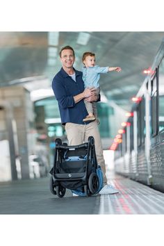 a man holding a small child while standing next to a train